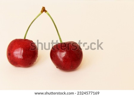 cherries isolated close up. Healthy food fruit red cherries on a light pink background