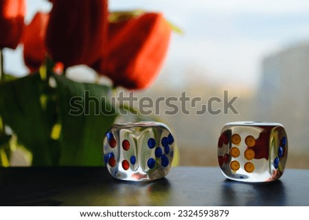 Transparent dice on the background of a window and a bouquet of red peonies Royalty-Free Stock Photo #2324593879