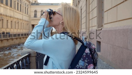 Mature tourist woman using vintage camera at city. Senior female photographer sightseeing and traveling in european city