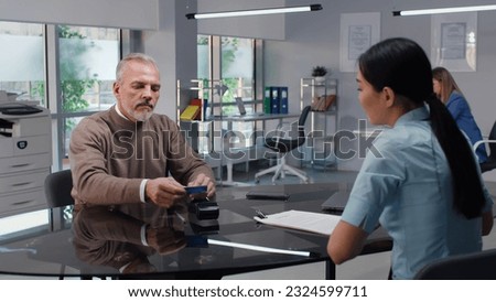 Mature man pay deposit with credit card in modern real estate agency. 