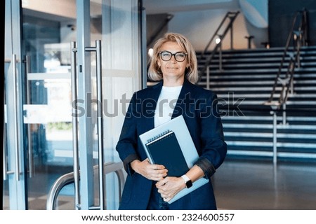 Smiling 50's stylish, confident mature businesswoman, middle aged company ceo director, experienced senior female professional, business coach team leader on office background. Female leader. Royalty-Free Stock Photo #2324600557
