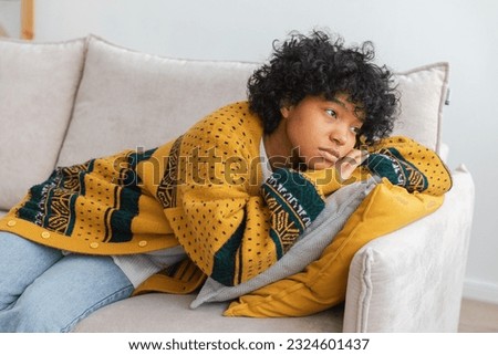 African american sad thoughtful pensive unmotivated girl sitting on sofa at home indoor. Young african woman ponder look tired after long day. Girl feels depressed offended lonely upset heartbreak Royalty-Free Stock Photo #2324601437