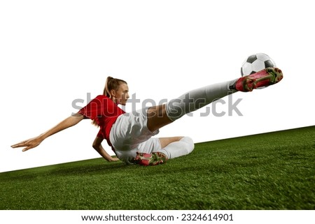 Motivated female athlete, young girl, football player kicking ball in motion on field grass against white background. Concept of professional sport, action, lifestyle, competition, hobby, training, ad Royalty-Free Stock Photo #2324614901