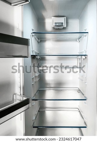 Front view of an empty fridge with glass shelves.