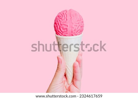 Ice cream cone topped with jelly-like human brain model in hand isolated on pink background. Mindful tasting adventure concept.