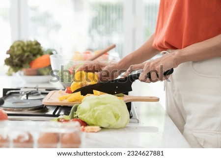 Hands of woman using knife cutting vegetables for cooking on table in kitchen room at home
