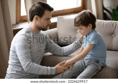 Loving young Caucasian father hug and cuddle unhappy small son, make peace reconcile after family fight. Caring dad comfort support upset sad little boy child feeling bad. Loner, depression concept. Royalty-Free Stock Photo #2324629917