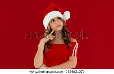 Photo of funny pretty lady celebrate winter holidays dreamy look empty space think family party hand on chin x-mas concept wear santa cap red isolated red color background