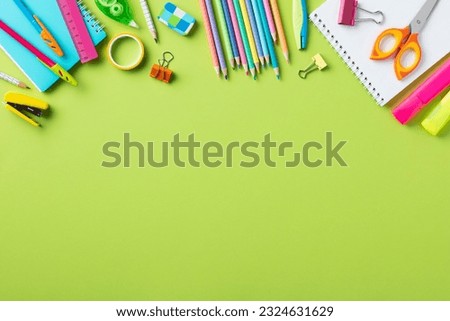 Back to school concept. Frame border made of school supplies on green background.