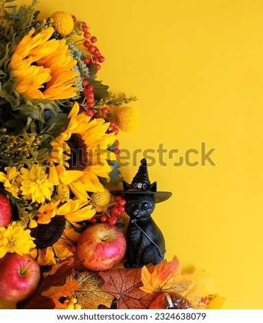 Magic black cat figurine, apples and autumn flowers bouquet on abstract yellow background. fall season. symbol of autumn season, thanksgiving, halloween, mabon. top view. template for design