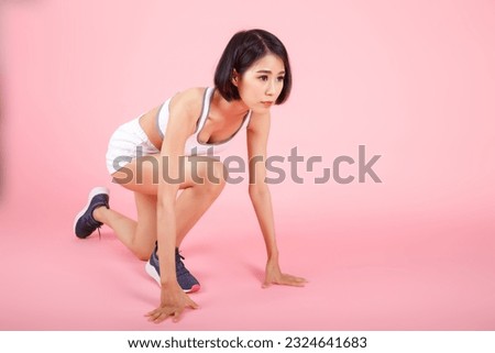 Sporty young woman in crouch start position isolated on pink background. Female Athlete Runner. Confident young female athlete in starting position ready to start a sprint. Royalty-Free Stock Photo #2324641683