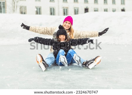 A little girl skater in a winter park having fun with her daughter