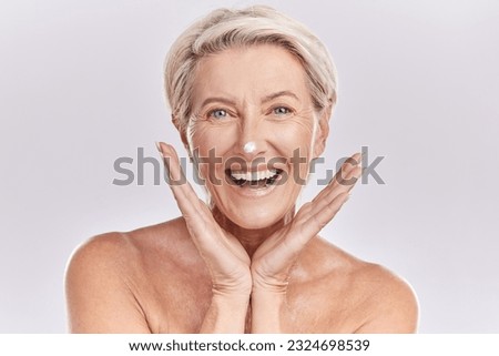 Skincare, portrait and mature woman with cream on face for anti aging, dermatology and collagen on white background. Facial, happy senior model with lotion or sunscreen in studio with beauty product.