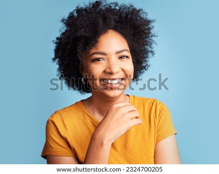Happy, smile and portrait of a woman in a studio with a positive, good and confident mindset. Happiness, excited and headshot of a young female model with an afro from Colombia by a blue background.