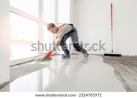 Leveling with mixture of cement for floors. Worker use screed concrete epoxy for level. Royalty-Free Stock Photo #2324701971