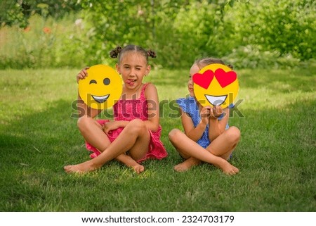 The girl makes faces, repeating the emoji. The child looks at his sister , closing eye with a yellow emoticon with hearts