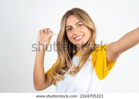 Young beautiful woman wearing football T-shirt over white background  make selfie holding an invisible braces aligner, recommending this new treatment. Dental healthcare concept.