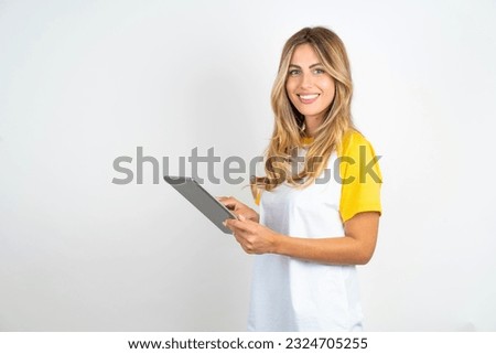 Photo of happy cheerful smart Young beautiful woman wearing football T-shirt over white background  hold tablet browsing internet Royalty-Free Stock Photo #2324705255