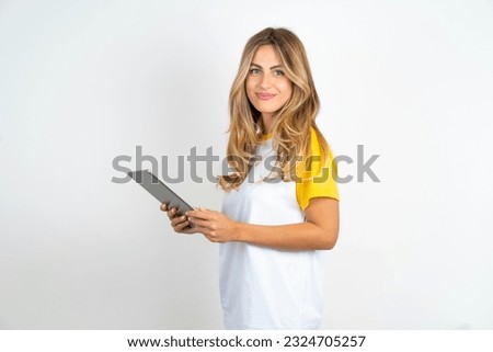 Photo of optimistic Young beautiful woman wearing football T-shirt over white background  hold tablet