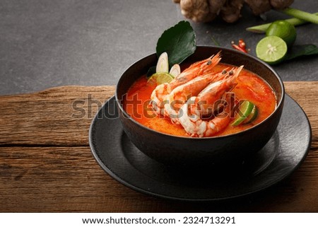Taste of Thailand: Spicy and Sour Thai Tom Yum Goong Soup with Shrimp and Aromatic Ingredients on Black and Wooden Background Royalty-Free Stock Photo #2324713291