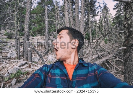 A frightened and lost male hiker looks around in the forest. The concept of meeting wild animals and phobia and accident in the woods Royalty-Free Stock Photo #2324715395