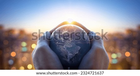 Planet Earth in the hands of a man against the background of the lights of the evening city. Concept and symbol on the theme of ecology, earth conservation. Elements of this image furnished by NASA. Royalty-Free Stock Photo #2324721637