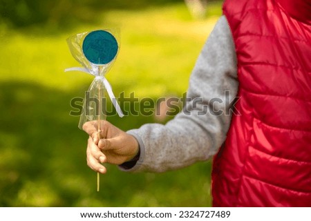 The child holds a blue lollipop in his hand.Treat the child with candy on a stick.Sweet treat.