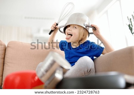 Mischievous preschooler boy play the music using kitchen tools and utensils at home during quarantine. Funny drum part from child. Entertainment a little kids at home. Royalty-Free Stock Photo #2324728763