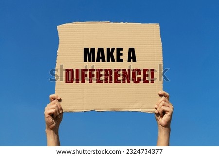 Make a difference text on box paper held by 2 hands with isolated blue sky background. This message board can be used as business concept to inform audience to make a difference.