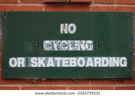 Green sign with white text in block capitals "No Cycling or Skateboarding"