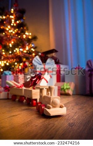 Wooden toy train with special gift and christmas tree on background.