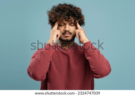 Portrait of sad Indian man touching head, headache, health problem, migraine, closed eyes isolated on blue background. Healthcare concept, upset male