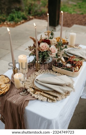 Romantic candle lit outdoor dinner for two with pink and red flowers Royalty-Free Stock Photo #2324749723