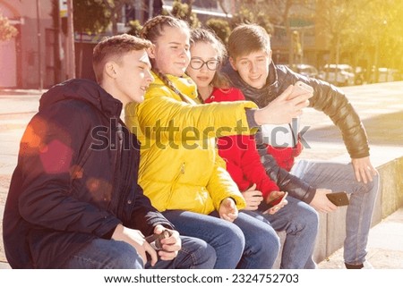Joyful teens take group selfie on city street