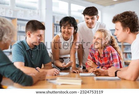 Teenagers in the school library are brainstorming together solving a difficult problem Royalty-Free Stock Photo #2324753119