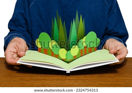 Trees in a pop-up picture book held by a person. (The paper craft in the book was made by myself.) Royalty-Free Stock Photo #2324754313