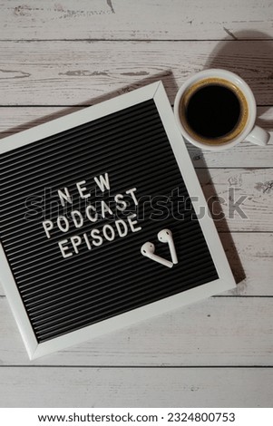 Announcement Letter board with text NEW PODCAST EPISODE on wooden table with white cup of coffee wireless headphones. Podcasting concept. Listening radio audio healing wellness sound Royalty-Free Stock Photo #2324800753