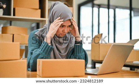Stressed Muslim online business owner feeling upset and unhappy about the sale and orders in her workplace