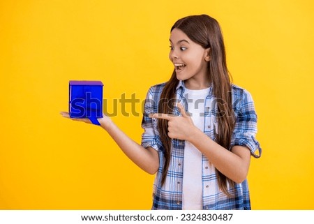 amazed teen girl shopping with present in studio. teen girl holding shopping box on background. teen girl after successful shopping. teen girl with shopping box isolated on yellow