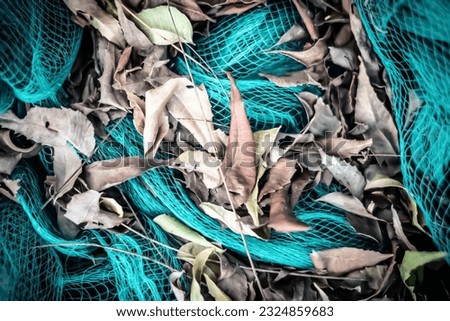 Close-up view of green nylon multi colorful bright fish nets in a pile of dry leaves in fishing village. Still life background pattern. Hobby fishing concept. Copy space. Autumn mood collection
