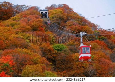 Tourists riding in cable cars of Akechidaira Ropeway up to a viewing platform to enjoy the panorama of mountains blanketed with vibrant fall colors, in Nikko National Park, Tochigi, Japan Royalty-Free Stock Photo #2324866217