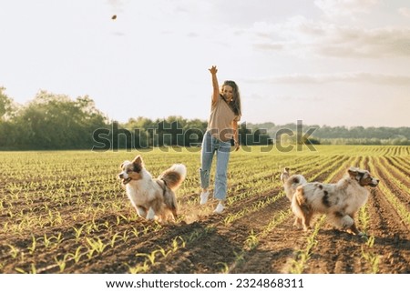 happy young woman playing with her dogs outdoors in the countryside Royalty-Free Stock Photo #2324868311