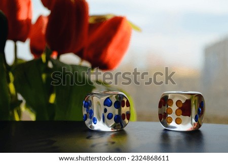 Transparent dice on the background of a window and a bouquet of red peonies Royalty-Free Stock Photo #2324868611