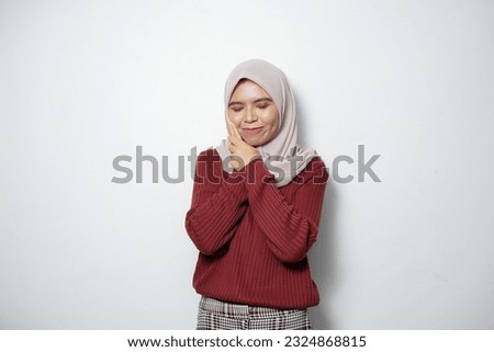 Young Asian Muslim woman feeling pain, holding her cheek with hand, suffering from severe toothache isolated over white background