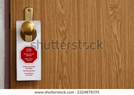 A "Do not disturb" sign in 6 languages hanging from the hotel room handle.
