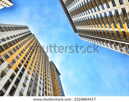 Point of view of a person looking up and seeing tall apartment buildings and clear blue sky.  Looking down, looking up.