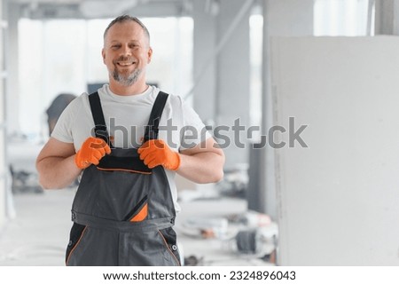 Portrait of a builder in the process of working on a construction site indoors. Royalty-Free Stock Photo #2324896043