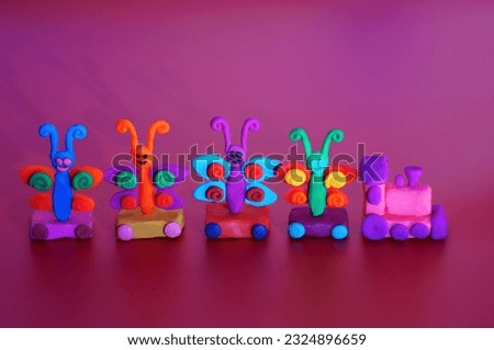 A toy train with colorful butterflies on a purple background. Children's toys. Decorations for the holiday.