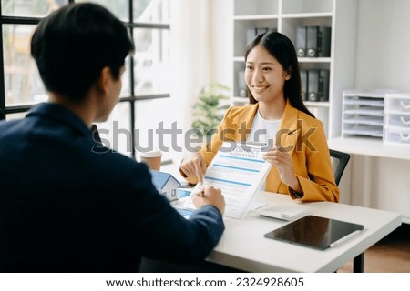 Asian Real estate broker agent presenting and consult to customer to decision making sign insurance form agreement, home model, concerning mortgage loan offer in office
