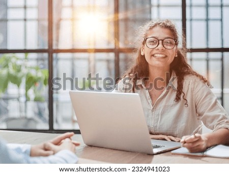 manager in glasses sitting at the table receives a client in the office